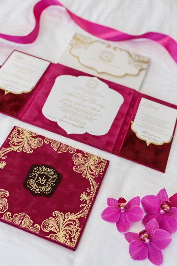 a bright fuchsia and hot pink wedding invitation suite with gold patterns, gold calligraphy and ribbon is amazing