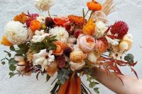 a bright orange wedding bouquet with burnt orange pieces, neutral and blush blooms, deep red ones and some greenery is wow