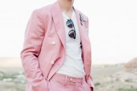 a bright pink groom’s suit with a white t-shirt, sunglasses and a unique boutonniere for an offbeat wedding