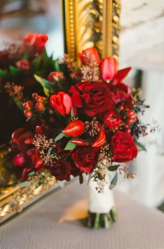 a bright red and burgundy Valentine wedding bouquet with berries and peppers is all about spicy love