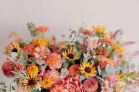 a bright summer wedding bouquet of pink and orange dahlias, some yellow and pink blooms and greenery is amazing