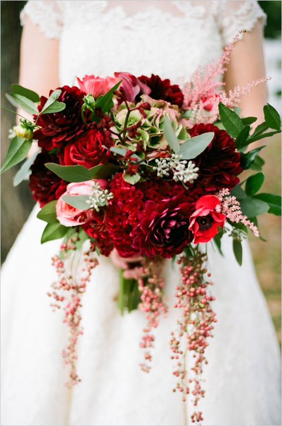 a bright wedding bouquet of burgundy peonies and red roses, pink blooms and red ranunculus, berries and greenery