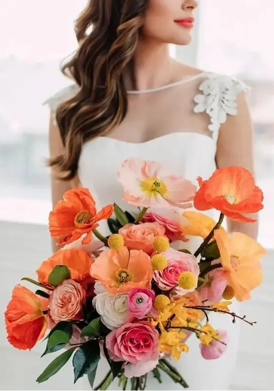 a bright wedding bouquet of orange and light pink poppies, white, orange and pink ranunculus, billy balls and some greenery