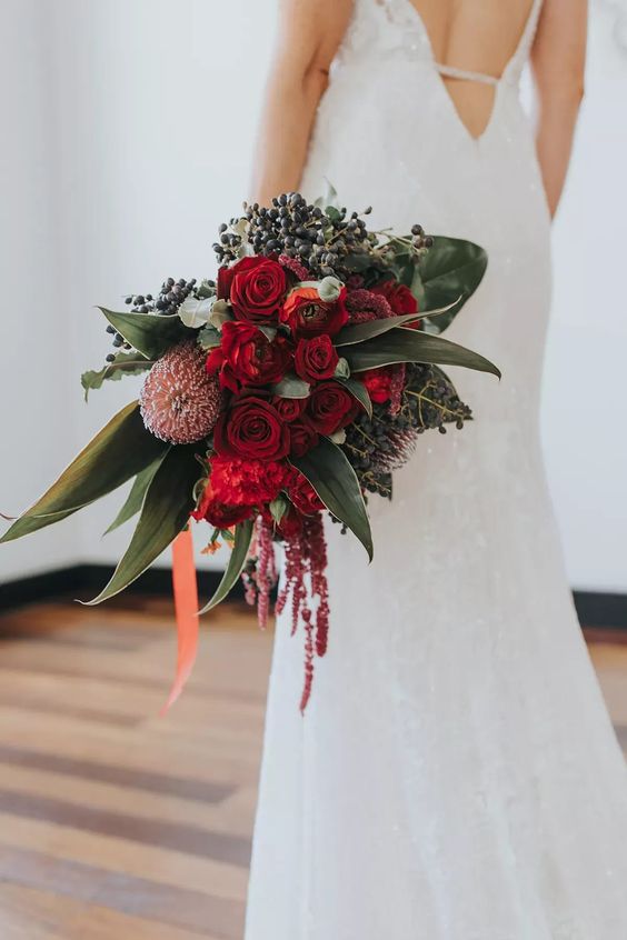 a catchy and textural wedding bouquet of red roses, anemones, peonies, privet berries, greenery and lisianthus is amazing