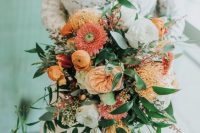 a catchy spring wedding bouquet with coral, yellow and orange blooms, berries and greenery is a lovely touch of color