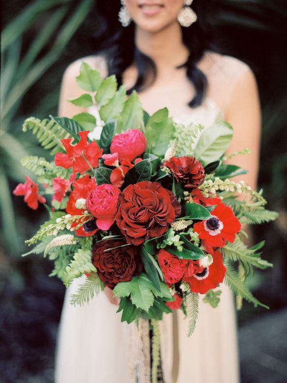 a catchy wedding bouquet of red peonies and anemones, greenery, leaves and fern is a wow idea with plenty of texture