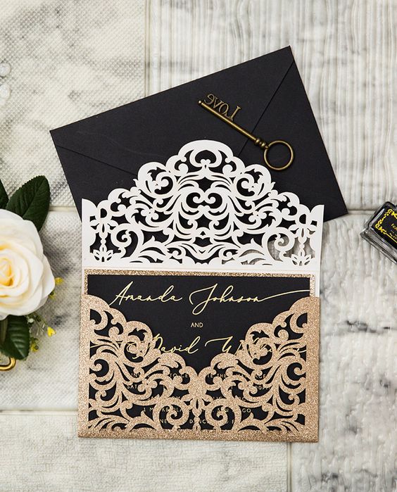 a chic Halloween wedding invitation suite with a black envelope and an invite, with a gold glitter laser cut jacket and gold calligraphy
