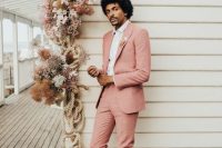 a classy modern gorom’s look with a pink pantsuit, pink velvet loafers and a white shirt plus a dried flower boutonniere