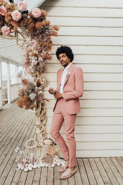 a classy modern gorom's look with a pink pantsuit, pink velvet loafers and a white shirt plus a dried flower boutonniere