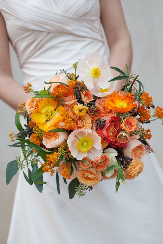 a colorful wedding bouquet of orange, yellow and blush blooms and greenery plus privet berries is amazing