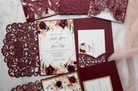 a colorful wedding invitation suite done in burgundy, with laser cut parts, with floral invitations and gold glitter touches