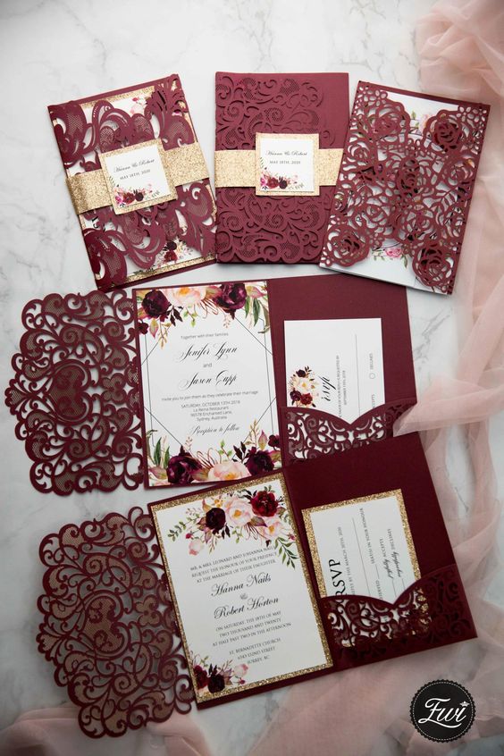 a colorful wedding invitation suite done in burgundy, with laser cut parts, with floral invitations and gold glitter touches