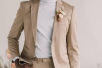 a cool minimalist groom’s look with a tan pantsuit, a neutral turtleneck and a dried flower boutonniere is pure perfection