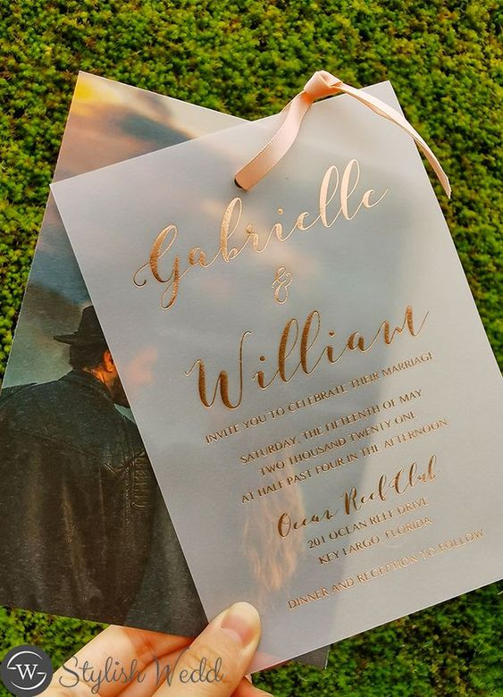 a creative wedding invitation with a couple's photo, a vellum invite with gold foil calligraphy and a pink ribbon is wow