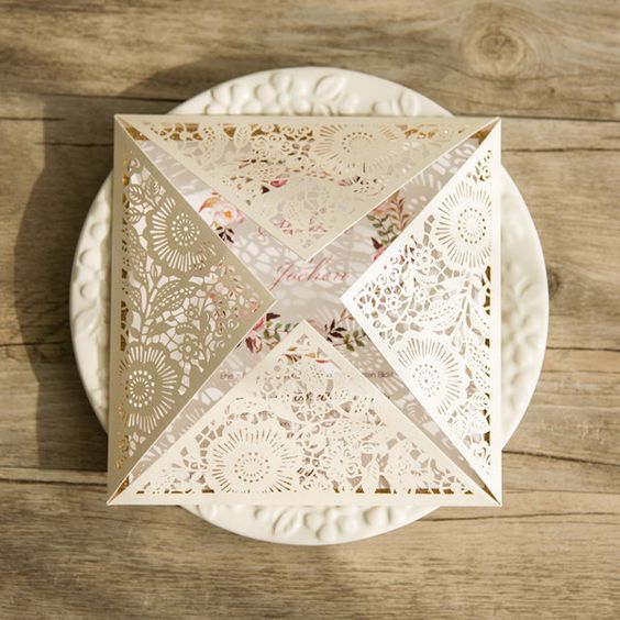 a floral invitation with a neutral floral laser cut cover with geometric angles for a romantic wedding