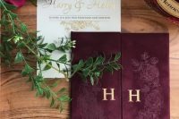 a gold calligraphy wedding invitation paired with a burgundy velvet cover with monograms is a very chic and lovely idea