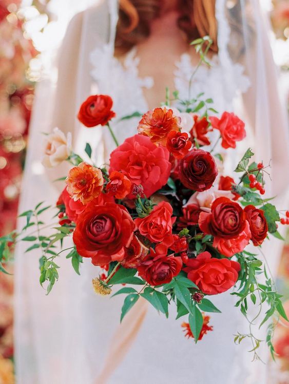 a gorgeous red wedding bouquet of roses and ranunculus and greenery plus some berries is a lovely idea for a fall wedding