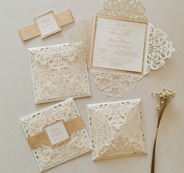 a jaw-dropping laser cut lace neutral wedding invitation suite with gold glitter ribbon and frames is amazing for a vintage neutral wedding