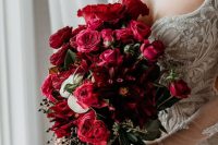 a lovely textural deep red and burgundy wedding bouquet of roses, greenery and berries is a stylish and bold idea for a colorful wedding