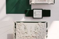 a lovely wedding invitation suite with a green envelope, white laser cut jackets, green ribbon and name accents is wow
