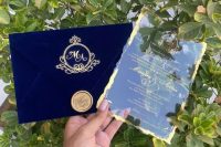 a lovely wedding invitation with a navy velvet envelope and gold calligraphy plus a gold seal, a clear acrylc invite with gold calligraphy