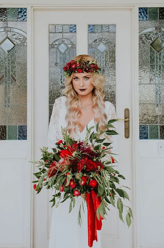 a lush cascading Christmas wedding bouquet with greenery and red blooms is Christmas classics