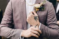 a mauve pantsuit, a white shirt, a cool floral boutonniere and a chunky chain as an accent in this ultra-modern groom’s look