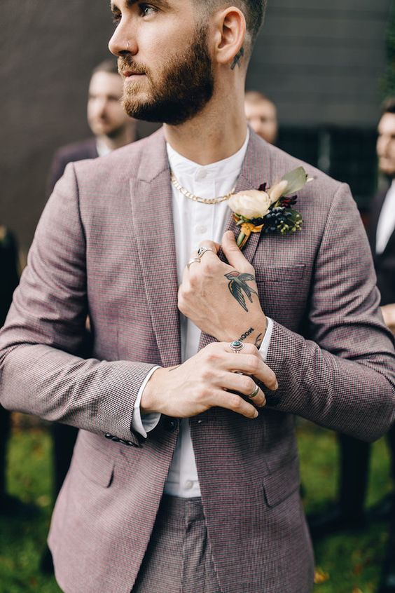 a mauve pantsuit, a white shirt, a cool floral boutonniere and a chunky chain as an accent in this ultra modern groom's look