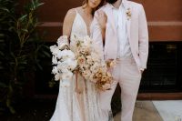 a minimalist groom’s outfit with a light pink pantsuit, a white shirt and white sneakers is a great spring or summer solution