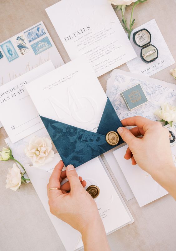 a modern romantic wedding invitation suite with neutral parts and black printing, with a blue velvet envelope with floral patterns