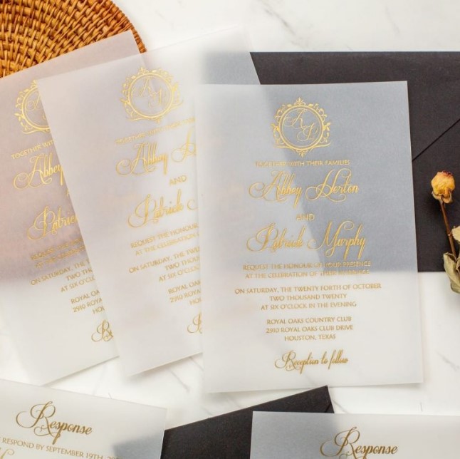 a modern wedding invitation suite with a black envelope and vellum invitations with gold foil calligraphy is a refined and chic idea