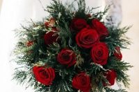 a simple holiday wedding bouquet of evergreens and red roses is a chic idea that always works