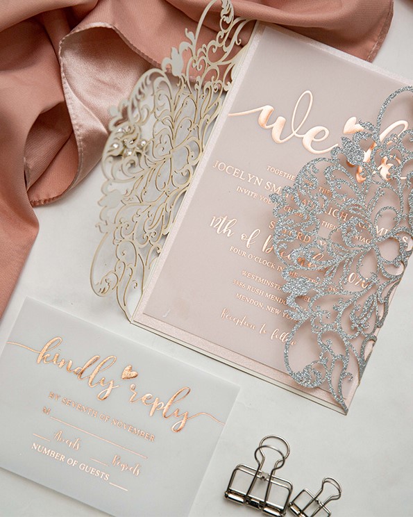 a sophisticated wedding invitation suite with a blush and vellum invitation with rose gold foiling and a laser cut sliver glitter jacket