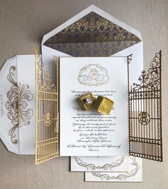 a sophisticated wedding invitation suite with a laser cut gate jacket, white invites and envelopes with gold calligraphy