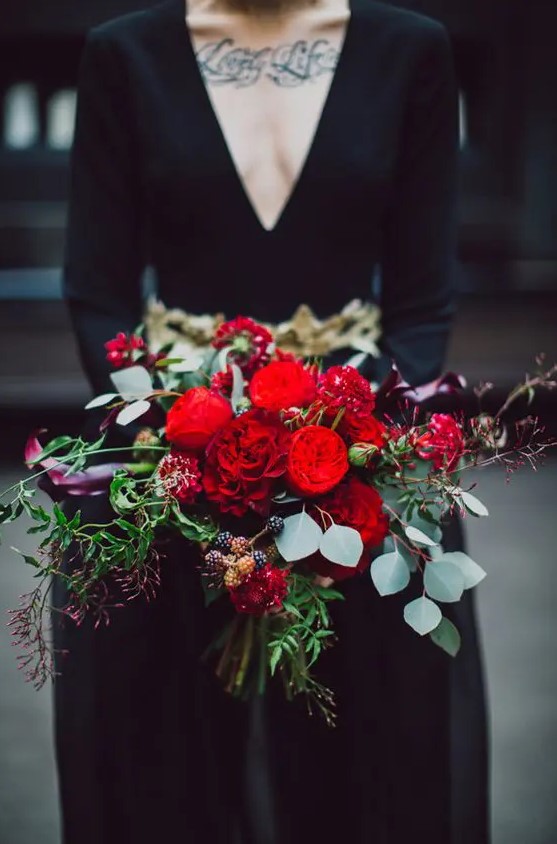 a super bold Halloween wedding bouquet with red and dark purple blooms plus berries and greenery