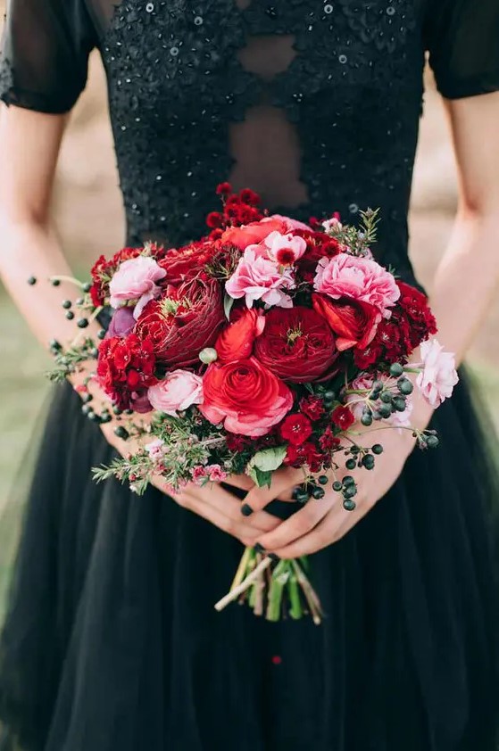 a super colorful wedding bouquet with red and pink blooms, greenery and berries