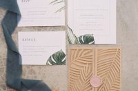 a tropical wedding invitation suite with tropical leaf prints and a laser cut leaf invitation jacket with a pink seal