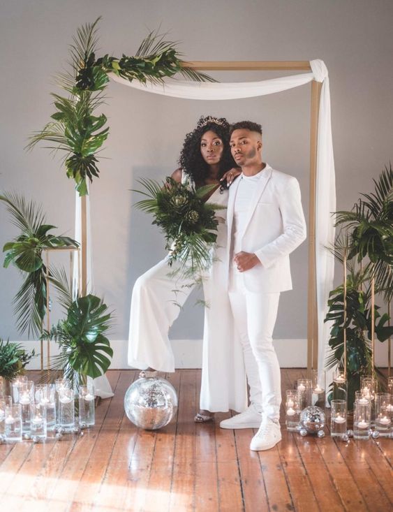 an all-white minimalist groom's look with a white pantsuit, a white t-shirt, sneakers is a lovely idea for a minimalist all-white wedding