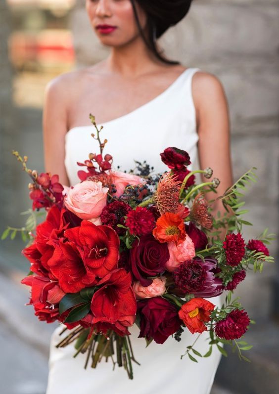 an extra bold wedding bouquet of red, burgundy and pink blooms, privet berries and greenery is amazing
