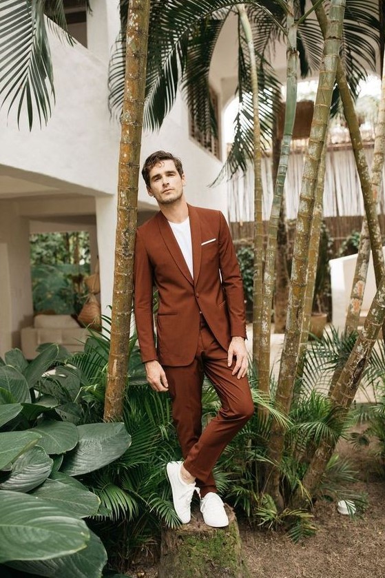 an ultra modern groom's look with a rust colored suit, a white t shirt, white sneakers is very laconic and stylish