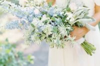 03 a beautiful wedding bouquet including white roses and blue delphinium and various types of greenery for a French country wedding
