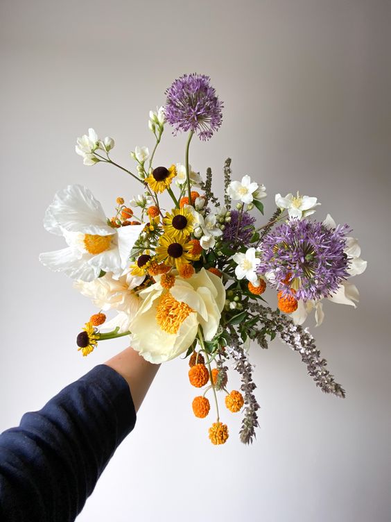 a unique bright wedding bouquet with white blooms, yellow and orange ones, with allium is a lovely idea for spring or summer