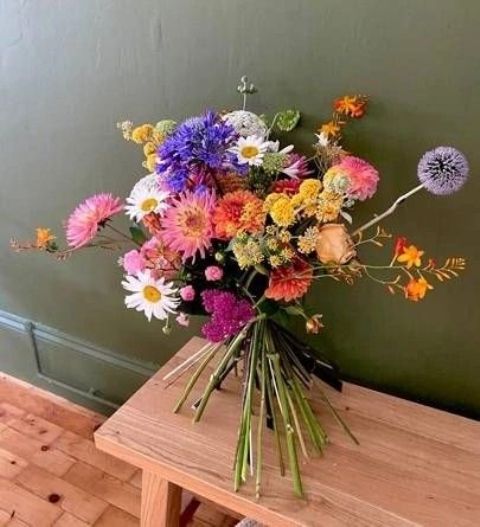 a bright wedding bouquet with dahlias, chamomiles, billy balls and many other blooms including allium is great for summer