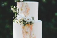10 a white wedding cake with peachy, yellow and blush watercolors, white blooms and greenery and a half moon cake topper