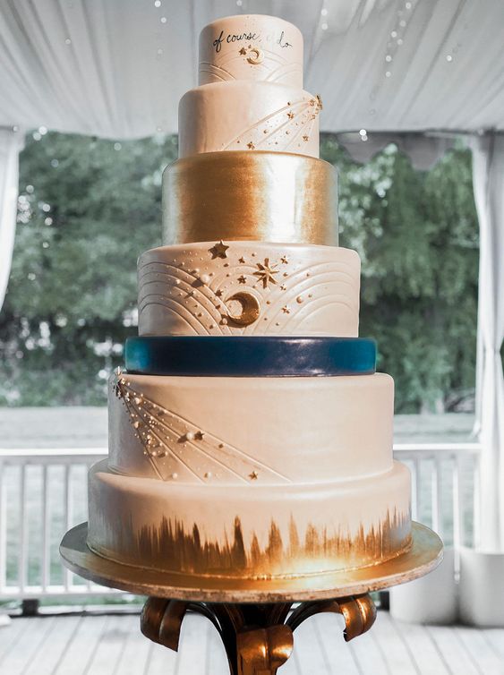 a white, navy and gold celestial wedding cake with stars, pearls, moons and some lettering is a gorgeous idea for a celestial wedding