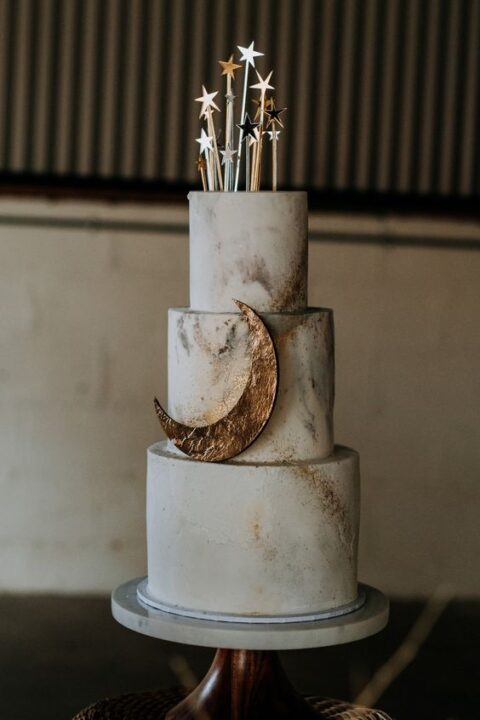 a neutral celestial marble effect wedding cake with a copper half moon and little star cake toppers is a lovely idea for a neutral celestial wedding