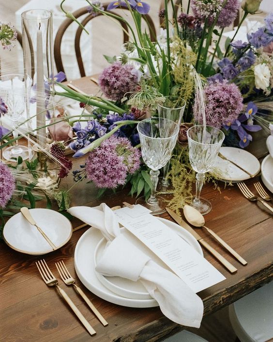 a beautiful and textural garden wedding centerpiece of allium, white ranunculus, purple irises and greenery is fantastic