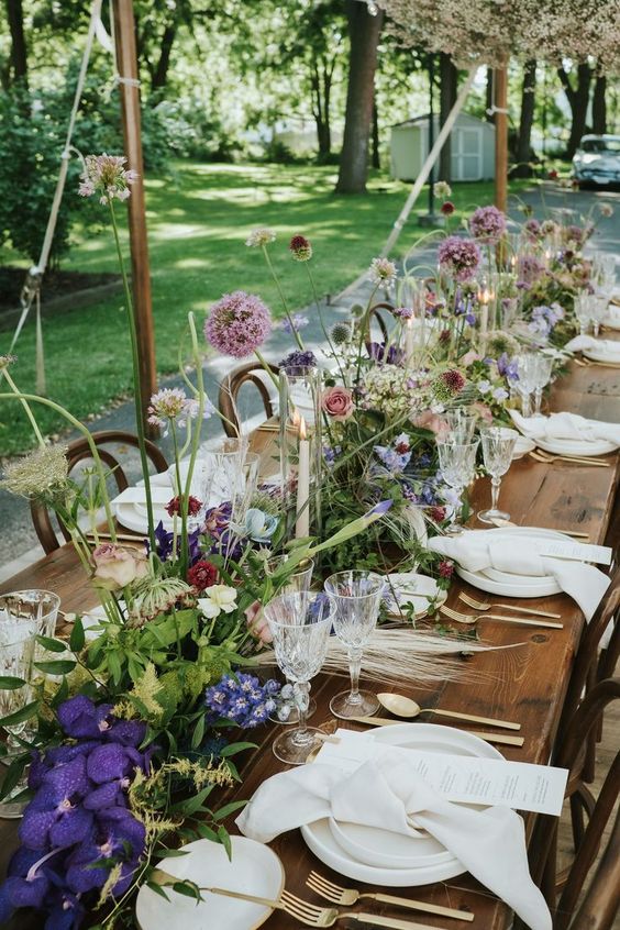 a beautiful secret garden wedding table runner with textural greenery, white, violet and mauve blooms, allium and pampas grass looks eye-catchy