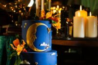 21 a bold blue wedding cake with gold stars and clouds, with a half moon and some sugar blooms is a catchy idea