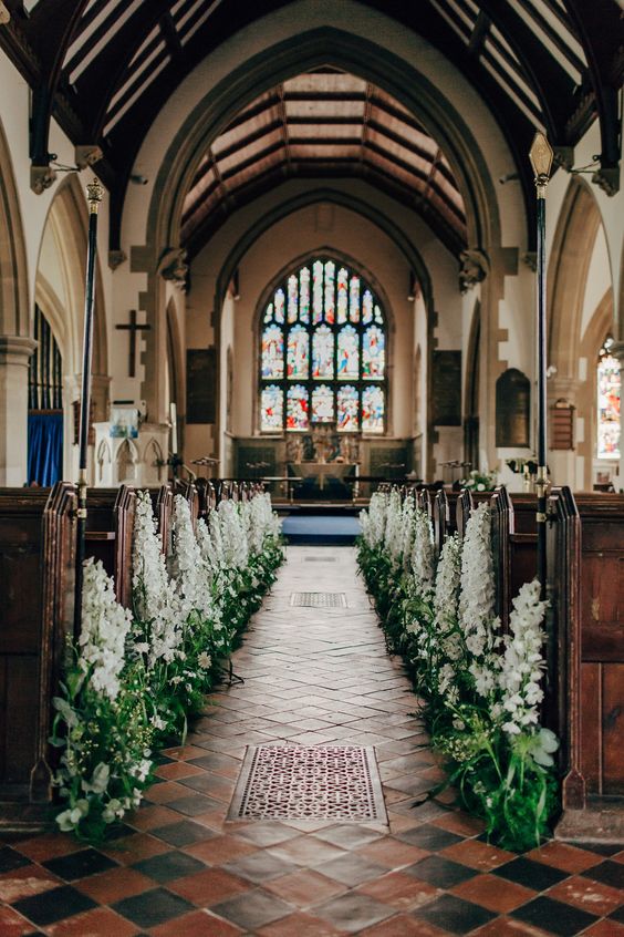 a church wedding aisle lined up with white delphinium and greenery is a gorgeous idea for a spring wedding